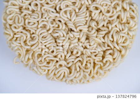 Uncooked instant noodles disk with detailed curly structure, neutral background and shallow depth of field emphasize starch strands, useful for ingredient and manufacturing visuals Uncooked instant noodles disk with detailed curly structure, neutral background and shallow depth of field emphasize starch strands, useful for ingredient and manufacturing visuals 137824796