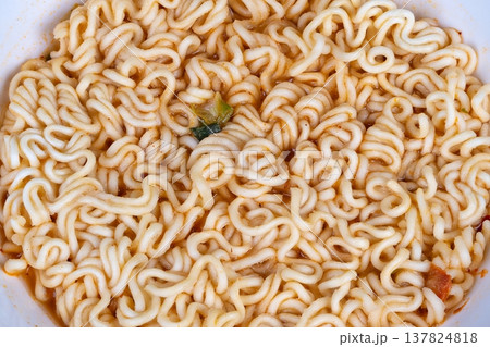 Closeup instant noodles with greens, simmered broth pooling around curly strands and tender texture, conveys quick homemade meal upgrade for cozy kitchen scenes and recipe content 137824818