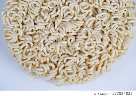Circular instant noodles piece ready for kitchen preparation, evokes quick meal planning and pantry staple use, neutral tones and tactile curls suggest fast comfort food 137824828