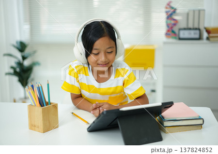 Asian girl with headphones enjoying online class on digital tablet Asian girl with headphones enjoying online class on digital tablet 137824852