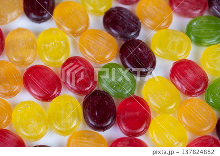 Multicolored candies evoke childhood nostalgia with glossy sheen, scattered composition, warm tones, white backdrop, playful mood for editorial lifestyle campaigns 137824882