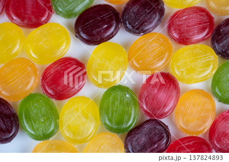 Seasonal multicolored hard candies arranged to evoke holiday stocking fillers, warm glow and nostalgic tone, suitable for greeting card or seasonal promotion visuals 137824893