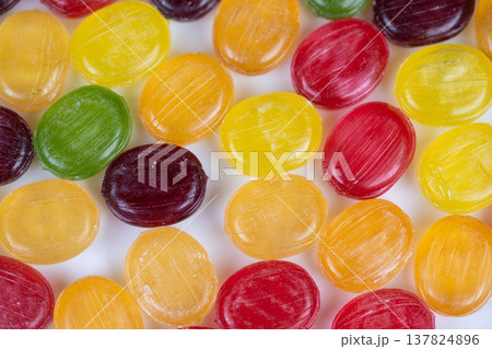 Softly lit multicolored hard candy closeup showing glossy surfaces and subtle highlights, minimalist background for texture studies or editorial food story, restrained palette 137824896