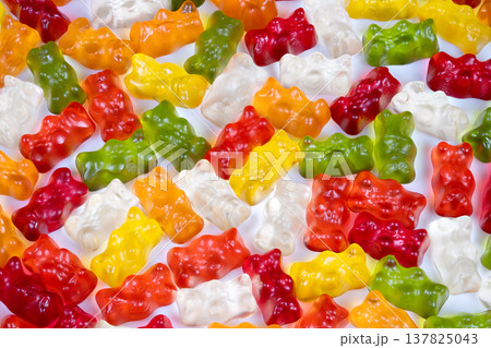 Closeup of vibrant gummy bears. Macro shot emphasizing glossy translucent gummy textures. Highresolution view highlighting refraction in multicolored gelatin candies 137825043
