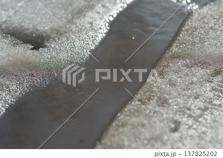 Glittering winter water stream scene. Radiant frozen brook flowing under sunlit highlights. Brilliant snowcovered creek with shimmering sunlight reflecting off icy surfaces 137825202