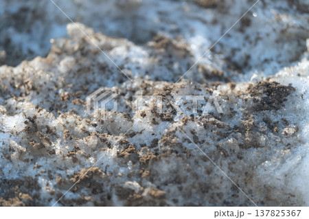 Snow with scattered dirt indicates need for street cleaning operations. Accumulation of melted snow blended with dirt signals importance of street maintenance schedules 137825367