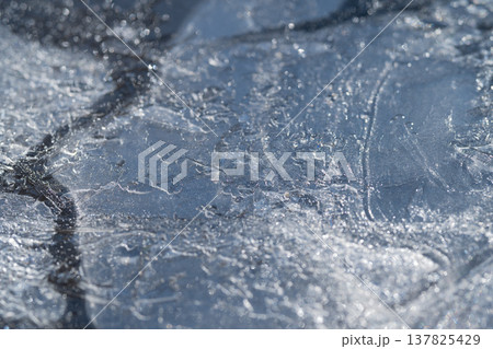 Ice surface intricacies. Frozen ice with delicate cracking. Cracked frozen surface shows frost and bubbles. Intricate frost and fractures adorn icy surface with reflections Ice surface intricacies. Frozen ice with delicate cracking. Cracked frozen surface shows frost and bubbles. Intricate frost and fractures adorn icy surface with reflections 137825429