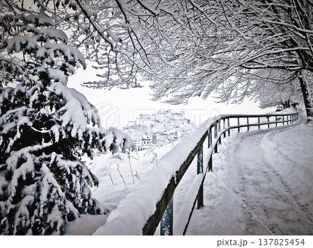 Winter wonderland Salzburg, Austria. Walk in the middle of February, on a snowy path on the Monchsberg, located near the historic city center of Salzburg, with a view of Hohensalzburg Fortress. Photo Winter wonderland Salzburg, Austria. Walk in the middle of February, on a snowy path on the Monchsberg, located near the historic city center of Salzburg, with a view of Hohensalzburg Fortress. Photo 137825454
