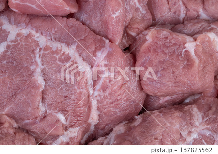 Piled high raw pork medallions with marbling ready for sale. Closeup of fresh raw pork medallions featuring pink marbling and granular texture under bright lighting Piled high raw pork medallions with marbling ready for sale. Closeup of fresh raw pork medallions featuring pink marbling and granular texture under bright lighting 137825562