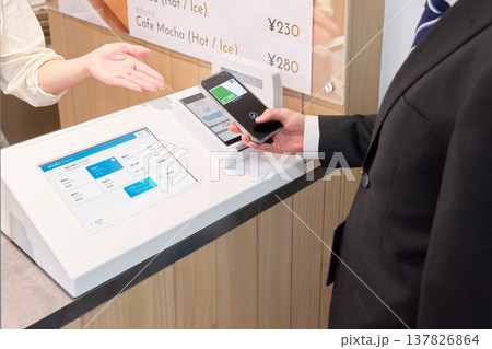 キャッシュレス決済をする客とサポートする店員の手元 137826864