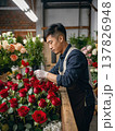 Asian man florist in market preparing spring peony, red rose and tulip bouquets for Hanami, Mother's Day and Tet festival. 137826948
