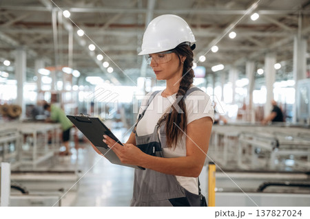 Female engineer is with notepad. Woman is in the window making factory Female engineer is with notepad. Woman is in the window making factory 137827024