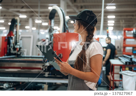 Notepad is in hands. Woman is in the window making factory Notepad is in hands. Woman is in the window making factory 137827067