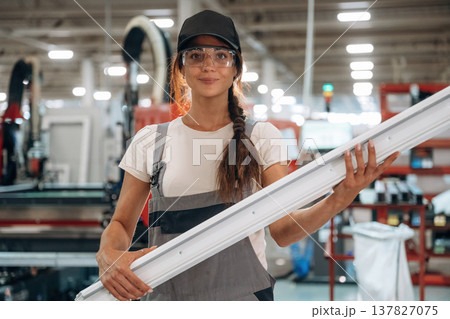 The part of frame in hands, plank. Woman is in the window making factory The part of frame in hands, plank. Woman is in the window making factory 137827075