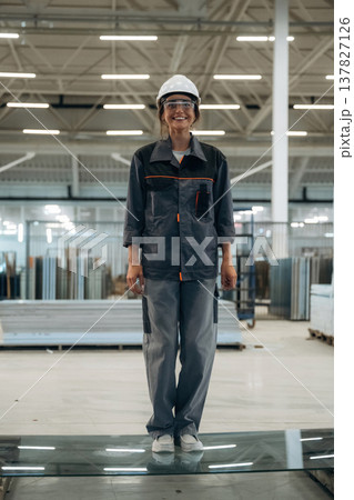 Testing toughness of the glass. Woman is in the window making factory Testing toughness of the glass. Woman is in the window making factory 137827126