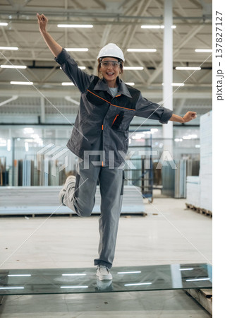 Testing toughness of the glass. Woman is in the window making factory 137827127