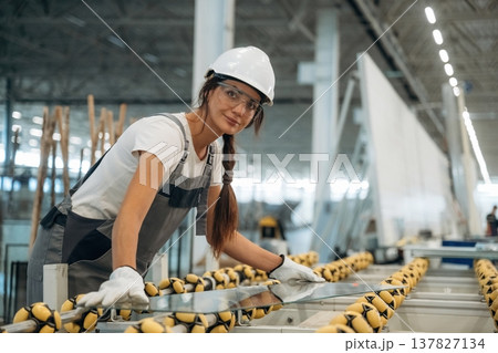 Conveyor with soft material and glass on it. Woman is in the window making factory Conveyor with soft material and glass on it. Woman is in the window making factory 137827134