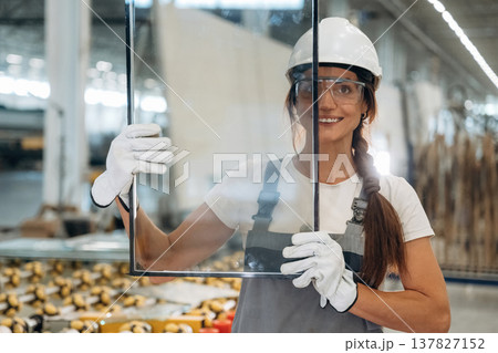 Little glass in hands. Woman is in the window making factory 137827152