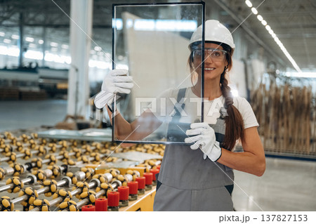 Little glass in hands. Woman is in the window making factory 137827153