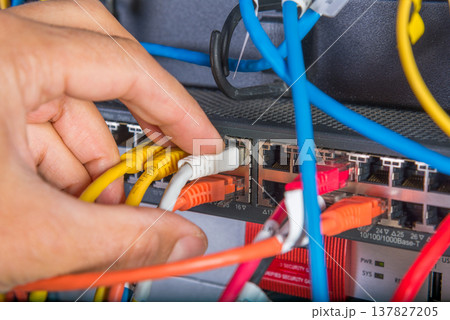 hand of engineer plugging in ethernet cable into server switch p 137827205