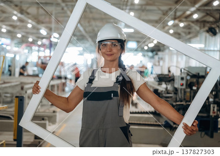 Big frame in hands. Woman is in the window making factory Big frame in hands. Woman is in the window making factory 137827303