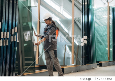 In gray uniform, with laptop. Woman is in the window making factory 137827368