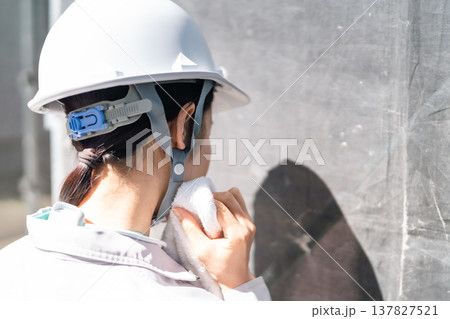 現場のリアリティ。猛暑の中、住宅リフォームを支える女性作業員のうなじに光る汗 137827521