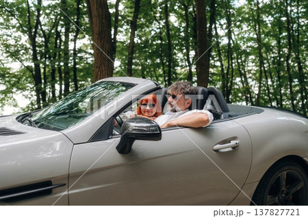 Road near the trees. Senior couple driving convertible cabriolet car Road near the trees. Senior couple driving convertible cabriolet car 137827721