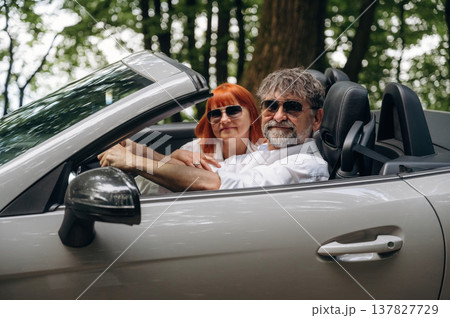 Wearing sunglasses, side view. Senior couple driving convertible cabriolet car 137827729