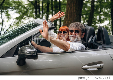 Wearing sunglasses, side view. Senior couple driving convertible cabriolet car 137827731
