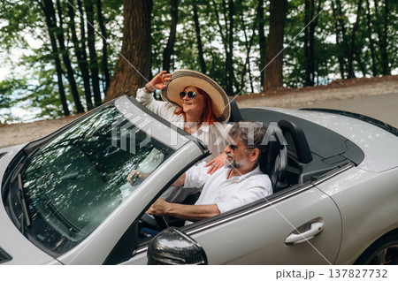 Wearing sunglasses, side view. Senior couple driving convertible cabriolet car 137827732