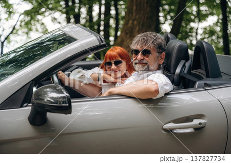 Wearing sunglasses, side view. Senior couple driving convertible cabriolet car 137827734