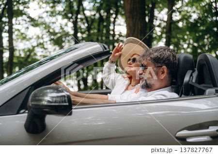 Enjoying the ride, in the hat, vacation. Senior couple driving convertible cabriolet car 137827767