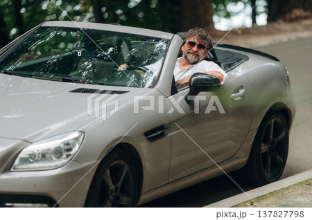 Looking at the camera. Stylish senior man is in convertible cabriolet car 137827798