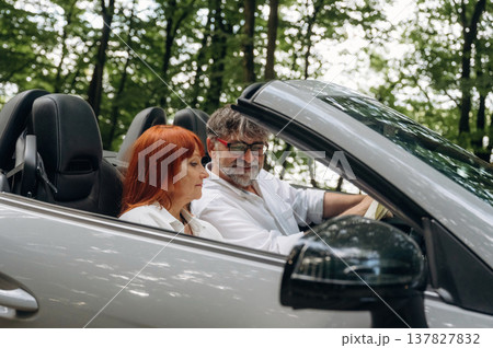 Riding and smiling. Senior couple driving convertible cabriolet car 137827832