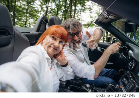 Making the selfie. Senior couple driving convertible cabriolet car Making the selfie. Senior couple driving convertible cabriolet car 137827849