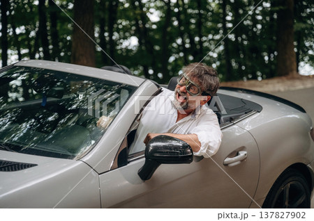 Retro aviator pilot glasses. Stylish senior man is in convertible cabriolet car 137827902