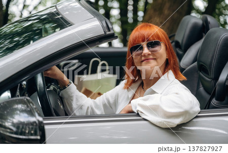 Having great time, in sunglasses. Side view of woman that is driving convertible cabriolet car 137827927