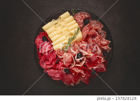 Cold cuts, appetizer, prosciutto, salami and ham, with maasdam cheese and olives, on a round plate, breakfast, top view, close-up, deserted 137828128