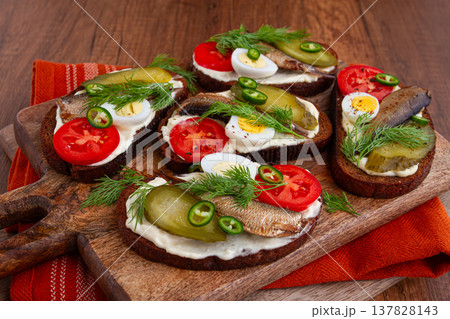open sandwiches with sprats, vegetables and herbs, on a wooden board, breakfast, snack, open sandwiches with sprats, vegetables and herbs, on a wooden board, breakfast, snack, 137828143