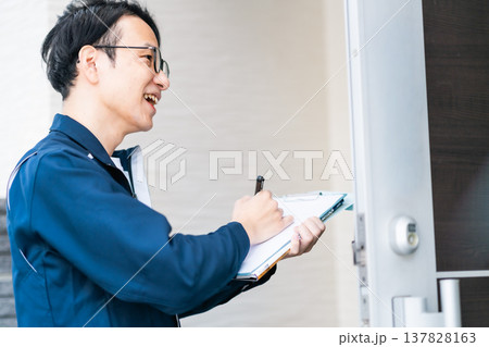 ライフラインの点検・訪問営業。クリップボードを手に、住宅の玄関先でヒアリングを行うエンジニア ライフラインの点検・訪問営業。クリップボードを手に、住宅の玄関先でヒアリングを行うエンジニア 137828163