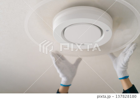 LED照明への交換作業を行う作業員のイメージ。天井のシーリングライトを取り付ける人物の手元(顔無し) LED照明への交換作業を行う作業員のイメージ。天井のシーリングライトを取り付ける人物の手元(顔無し) 137828180
