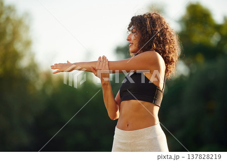 Hands exercises. Young fitness woman is on the field outdoors Hands exercises. Young fitness woman is on the field outdoors 137828219