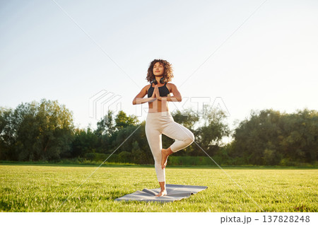 Classic tree yoga exercise for balance. Young fitness woman is on the field outdoors Classic tree yoga exercise for balance. Young fitness woman is on the field outdoors 137828248