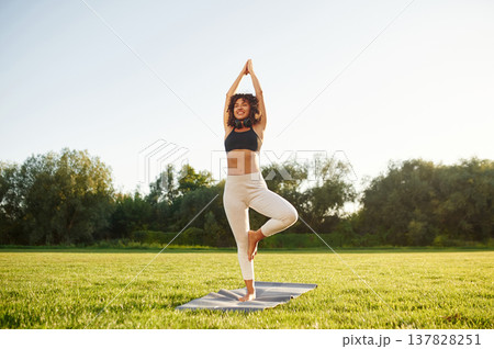 Classic tree yoga exercise for balance. Young fitness woman is on the field outdoors Classic tree yoga exercise for balance. Young fitness woman is on the field outdoors 137828251