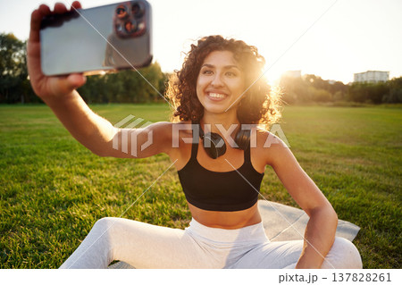 Selfie time. Young fitness woman is on the field outdoors Selfie time. Young fitness woman is on the field outdoors 137828261