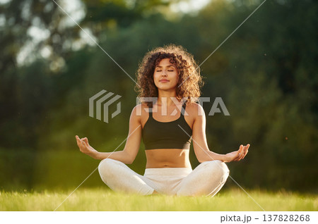 Meditation practice, in lotus pose. Young fitness woman is on the field outdoors 137828268