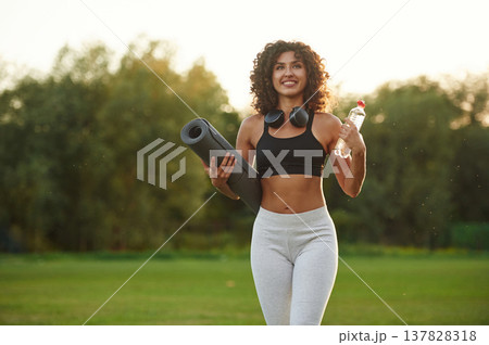 Hydration conception, holding bottle of water. Young fitness woman is on the field outdoors Hydration conception, holding bottle of water. Young fitness woman is on the field outdoors 137828318