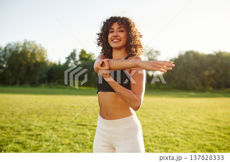 Getting ready, warm up exercises. Young fitness woman is on the field outdoors Getting ready, warm up exercises. Young fitness woman is on the field outdoors 137828333