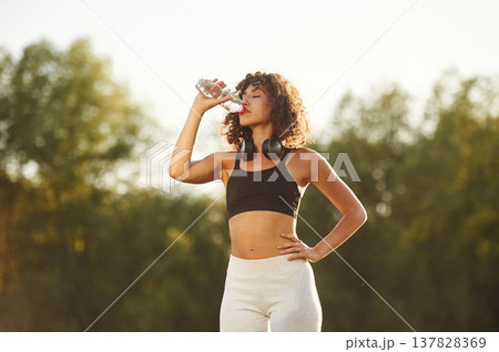 Break time, with bottle of water. Young fitness woman is on the field outdoors 137828369